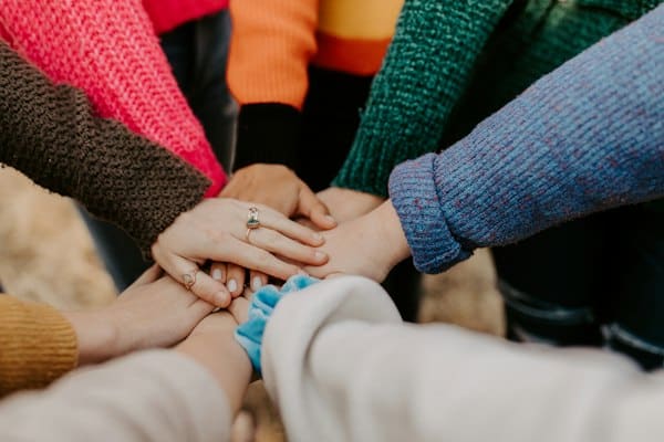 Mains de professionnels de santé et du social réunies en signe de cohésion