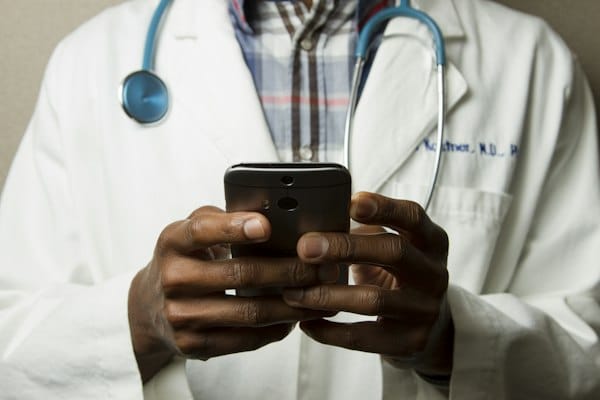 Soignante en blouse médicale consultant son téléphone dans un couloir